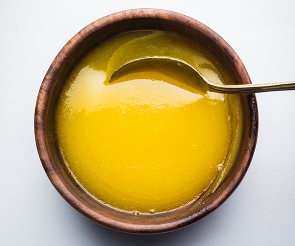 Ghee or clarified butter close up in wooden bowl